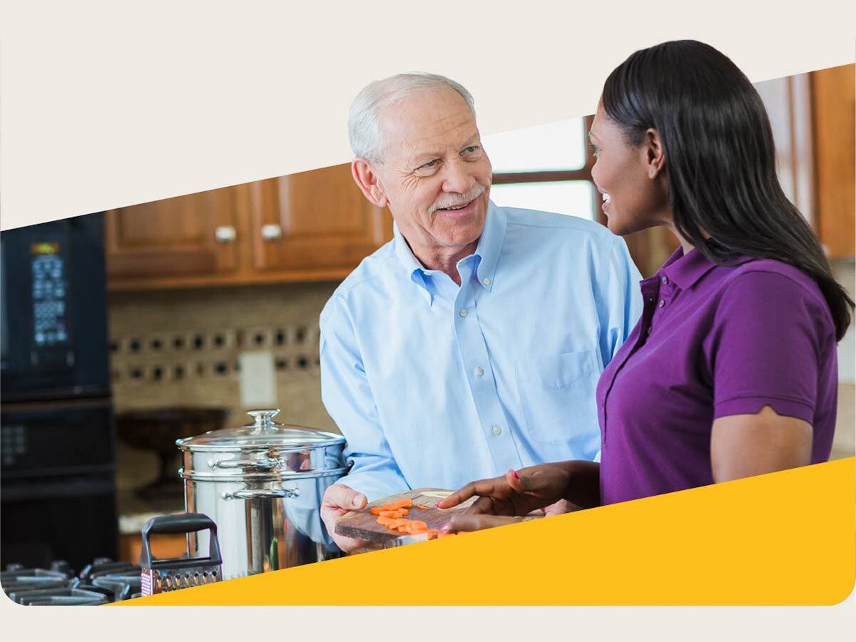 Aging man and Care Professional smile and prepare food together