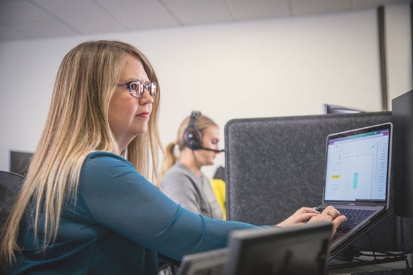 Woman enters information on laptop in office